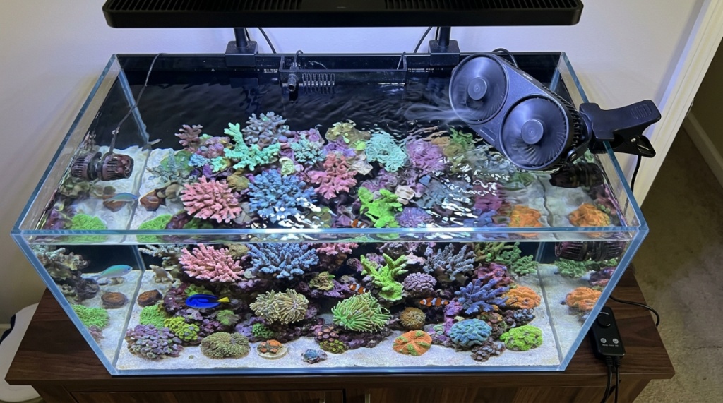Black mini aquarium cooling fan clamped to glass rim of planted fish tank.